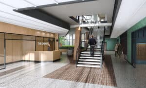 Modern lobby with a reception desk labeled "The Garrett," a staircase, terrazzo flooring, and people walking. | DC Apartments by WC Smith