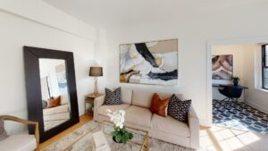 living area with sofa, coffee table, decorative mirror, and view of kitchen at the dahlia apartments in washington dc