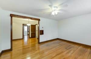 vacant living area with wood floors, ceiling fan and dark doorway accents at 2629 39th Street apartments in washington dc