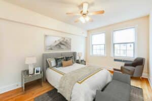 bedroom with bed, nightstand, sitting area, large windows, wood flooring and ceiling fan at 2800 ontario road apartments in adams morgan washington dc
