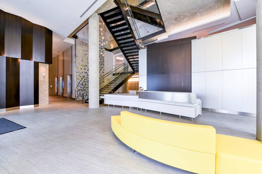 lobby with concierge desk, social seating and grand staircase at agora apartments in washington dc