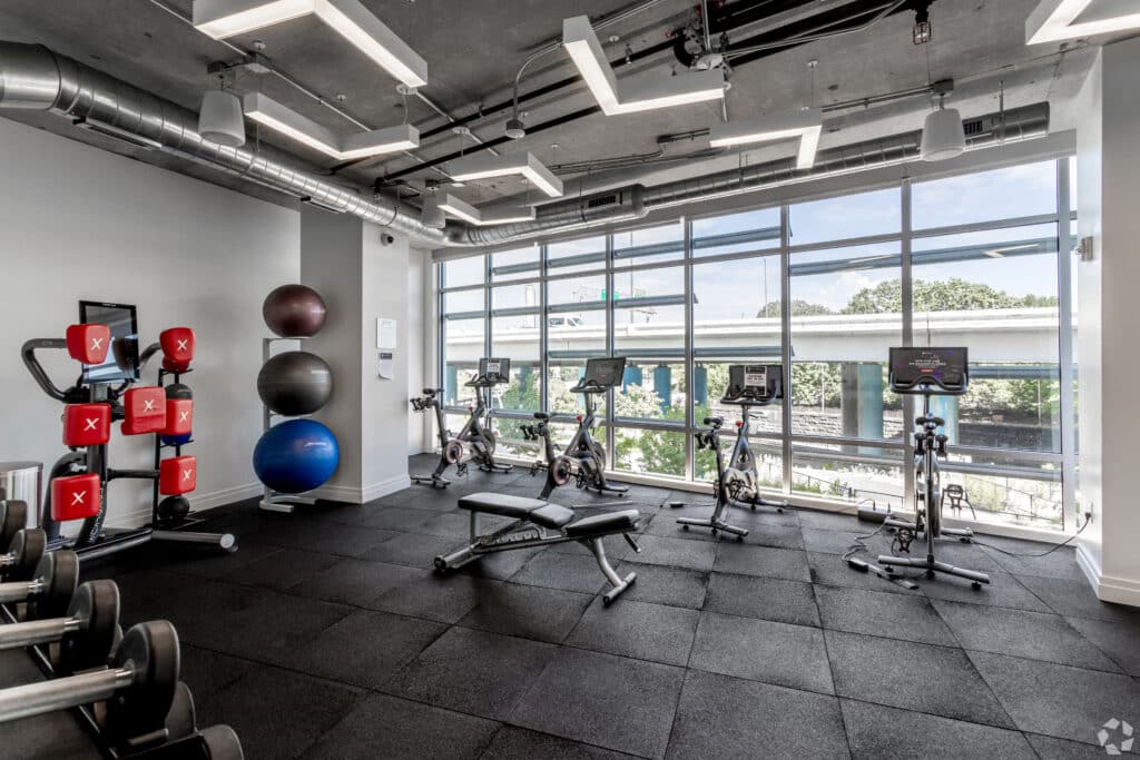 fitness center with peleton spin bikes, exercise balls, free weights and large windows at agora apartments in washington dc