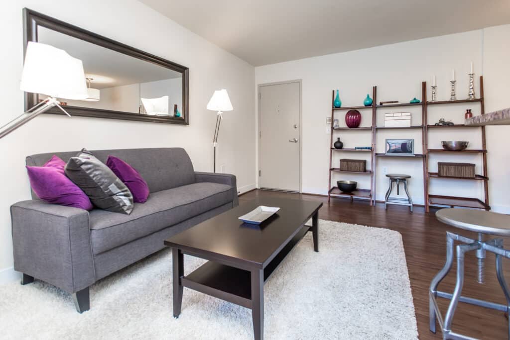 living area with sofa, coffee table, decorative mirror and bookshelves at fairway park apartments in washington dc