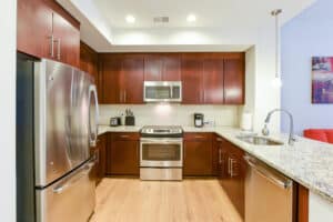 kitchen with stainless steel appliances, wood flooring and dark wood cabinetry at park chelsea apartments in washington dc