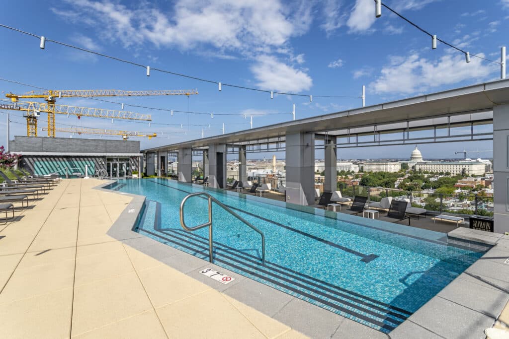 rooftop pool with lounge seating, and view of the united states capitol building at agora apartments in washington dc